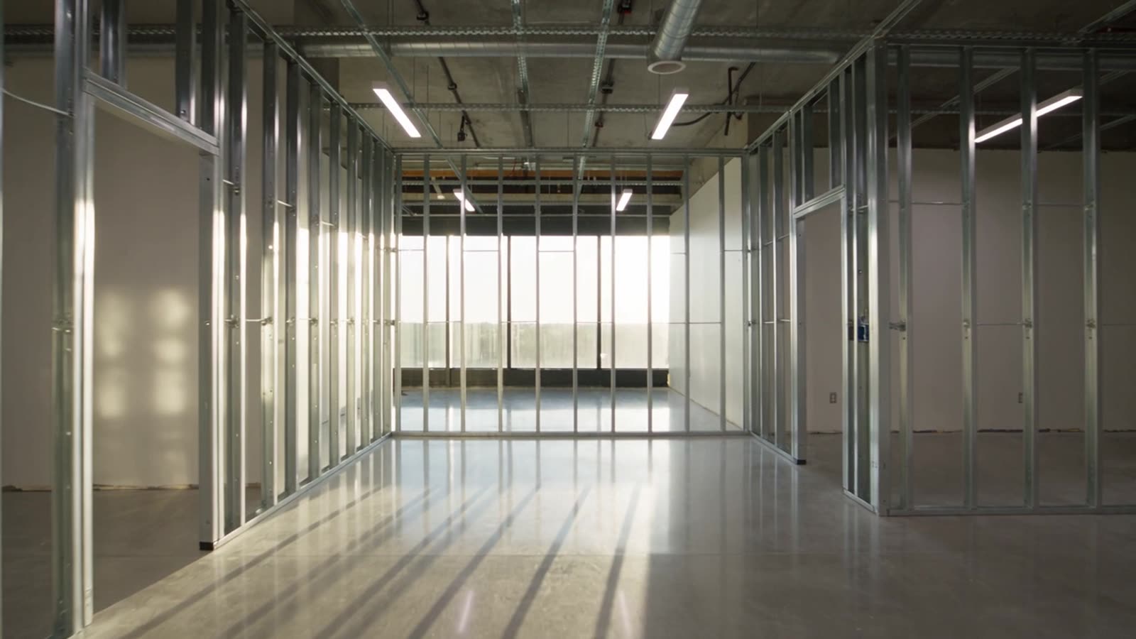 Rendering of a medical suite during build-out with framed walls, polished concrete and floor plans on a table